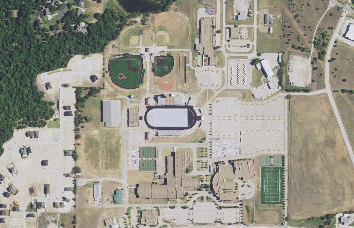 Aerial photograph of the Aledo High School campus with the football stadium, tennis courts and parking lots, houses to the south.