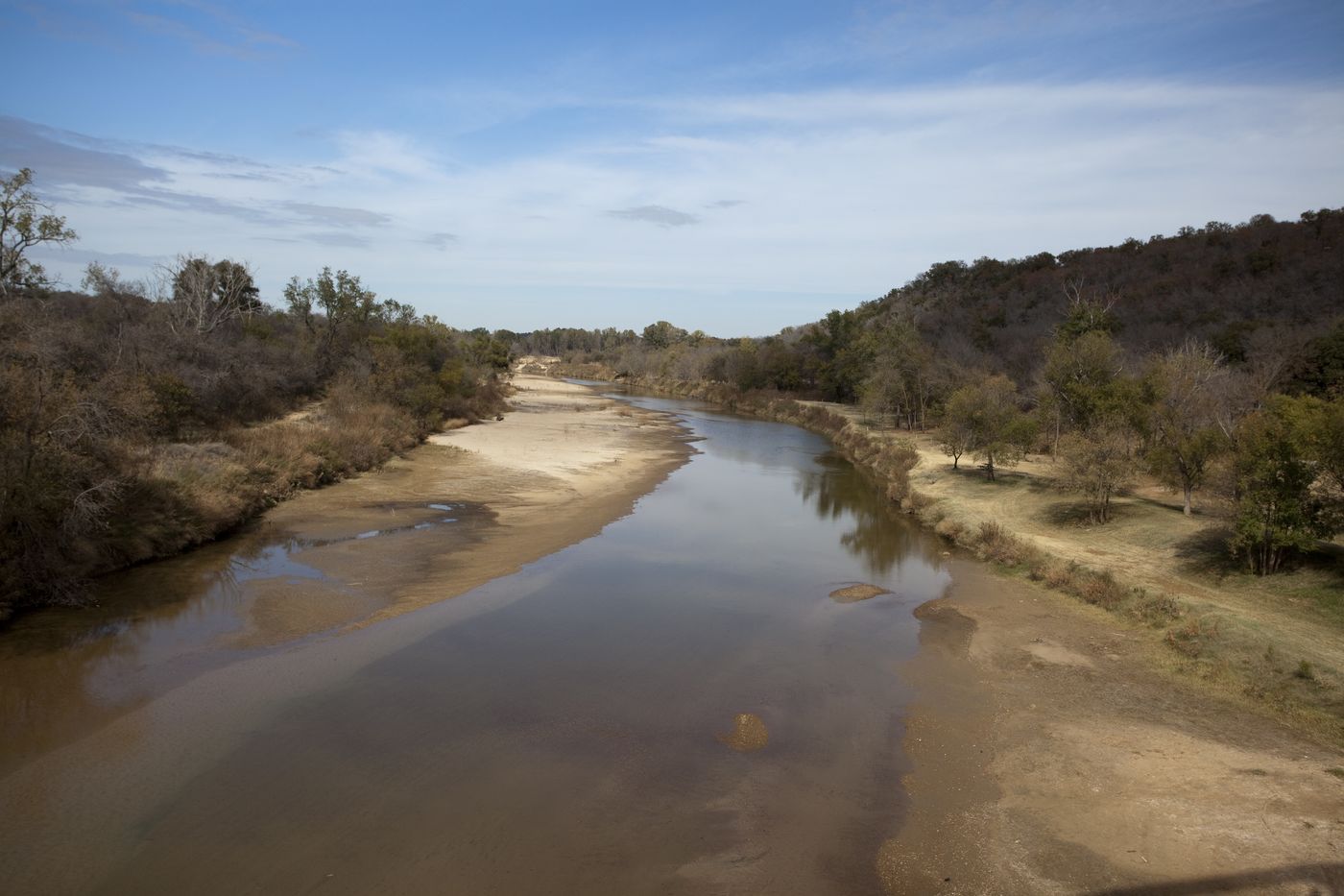 The Brazos River winding between sandbars and wooded banks north of Interstate 20 in Parker County, Texas.