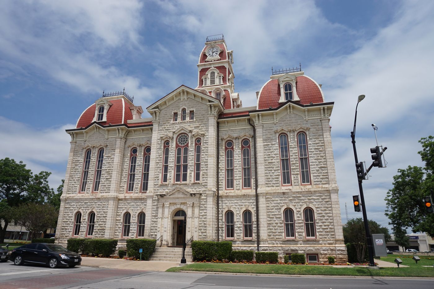 The 1886 Parker County Courthouse in Weatherford, Texas, a limestone Second Empire building with red mansard roofs and a central clock tower.