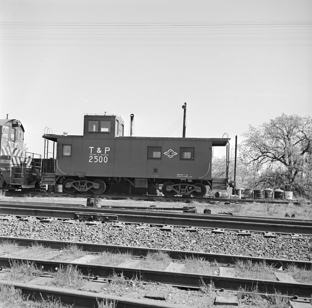 Black-and-white photograph of Texas and Pacific caboose number 2500 on a siding.
